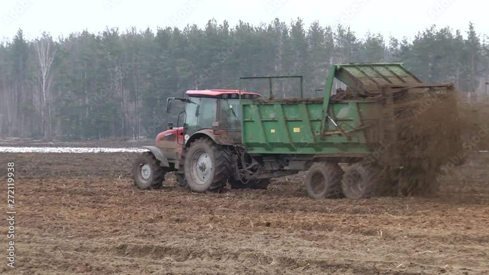A farmer using a manure spreader behind his tractor to spread an organic mixture of manure and hay on his land for fertilisation. Manure is used as fertilizer in agriculture. Concept: agriculture A farmer using a manure spreader behind his tractor to spread an organic mixture of manure and hay on his land for fertilisation. Manure is used as fertilizer in agriculture. Concept: agriculture