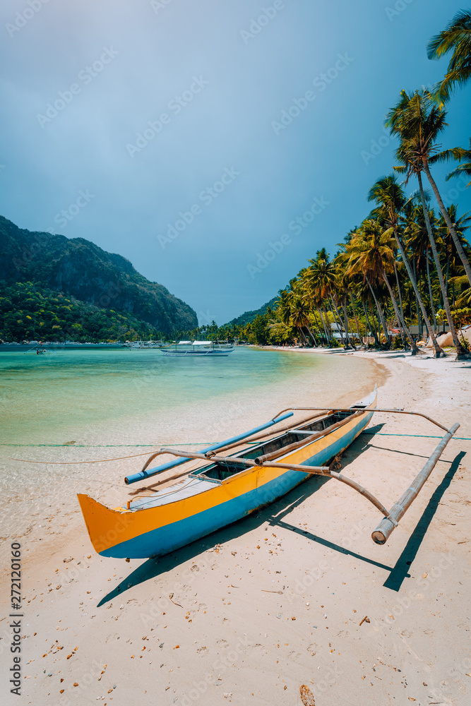 Traditional wooden banca boat on beautiful Las Cabanas beach. Summer vacations, Island hopping, El Nido, magic of Philippines