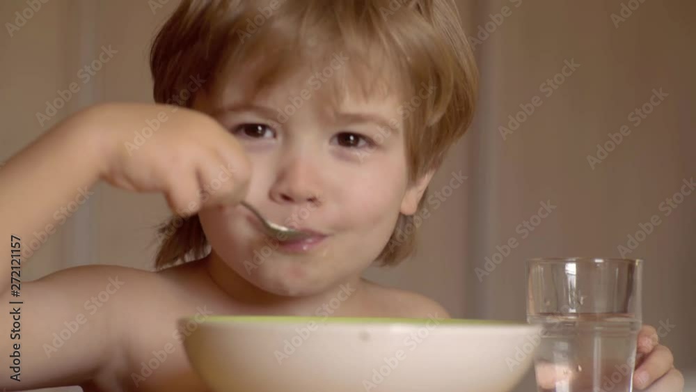 Little boy having breakfast in the kitchen. Little baby are eating. Hungry little boy eating. Young kid sitting on the table eating healthy food with funny expression on face. Little boy having breakfast in the kitchen. Little baby are eating. Hungry little boy eating. Young kid sitting on the table eating healthy food with funny expression on face.