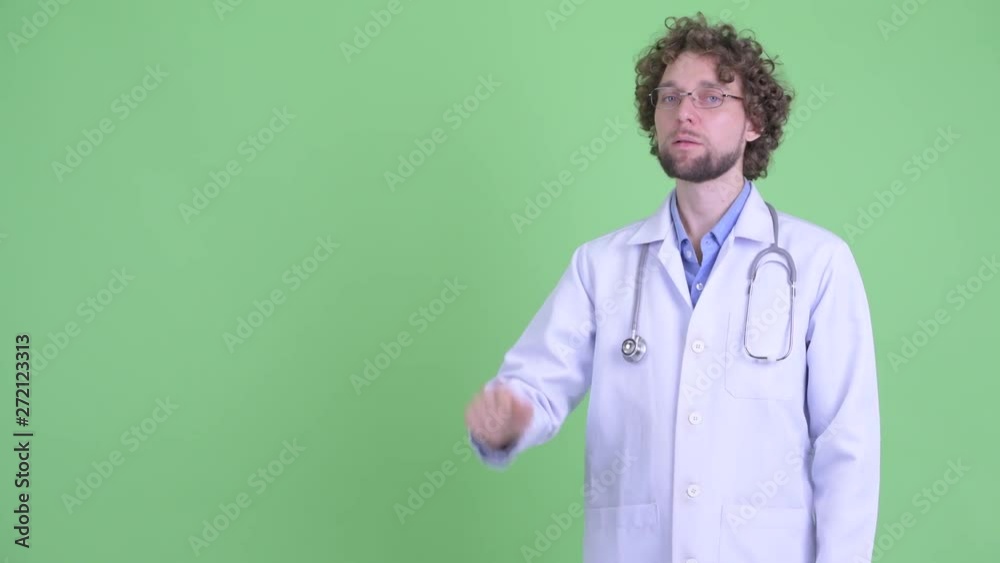 Happy young bearded man doctor touching something and giving thumbs up Happy young bearded man doctor touching something and giving thumbs up