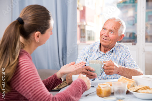 Mature father talks to adult daughter at the table. Tea party