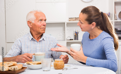 Mature man with daughter talking at table with cup of tea