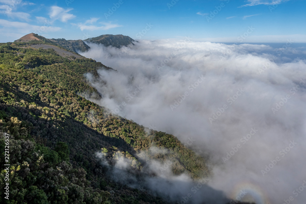 Nubes cubriendo montaña volcánica en isla