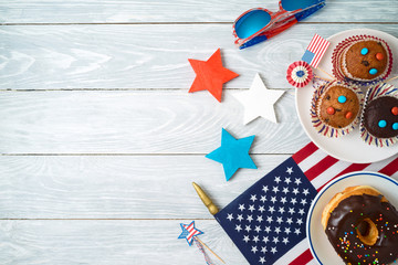 Happy Independence Day, 4th of July celebration concept with cupcakes, donuts and american flag on wooden background.