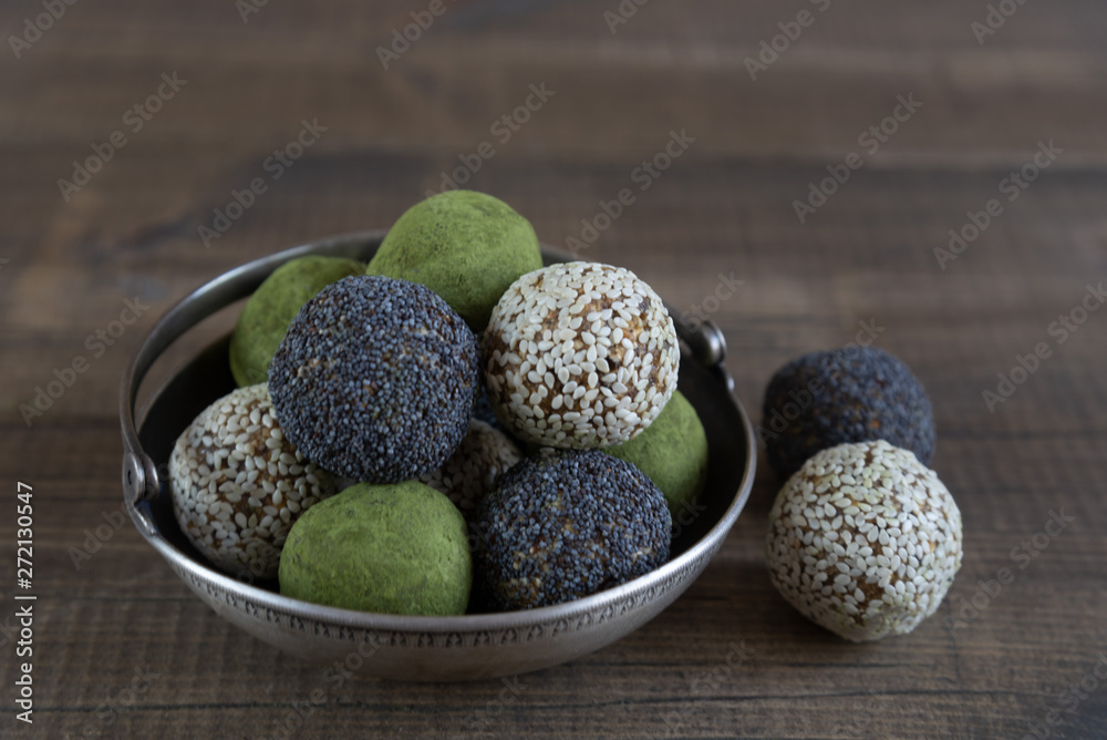 Handmade energy balls with poppy, sesame and matcha tea in vintage bowl on dark wooden background. Close up Handmade energy balls with poppy, sesame and matcha tea in vintage bowl on dark wooden background. Close up