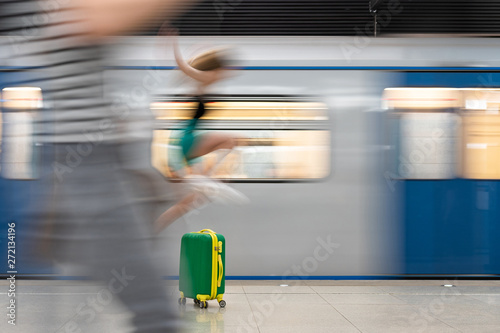 green bright road suitcase. A young beautiful girl walks around him and an action takes place. Blurred motion, very impressive. Lots of copy space © Денис Бухлаев