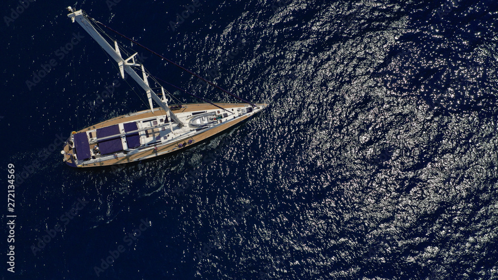 Fototapeta premium Aerial drone top view photo of sail boat sailing in mediterranean Aegean island of Santorini, Cyclades, Greece
