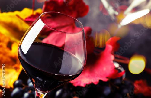 Red wine in wine glass, autumn still life with red and yellow leaves, wine tasting, copy space, selective focus photo