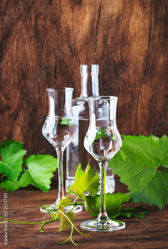 Grape vodka, pisco - traditional Peruvian strong alcoholic drink in elegant glasses on vintage wooden table, copy space photo