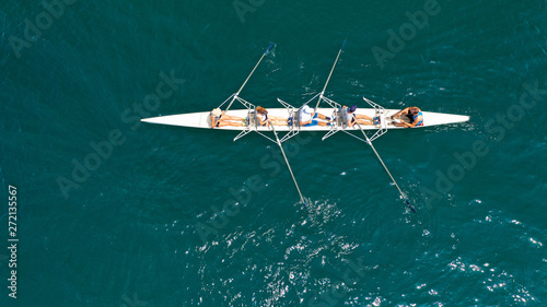 Aerial drone bird's eye view of sport canoe operated by team of young trained athletes in deep blue Aegean sea