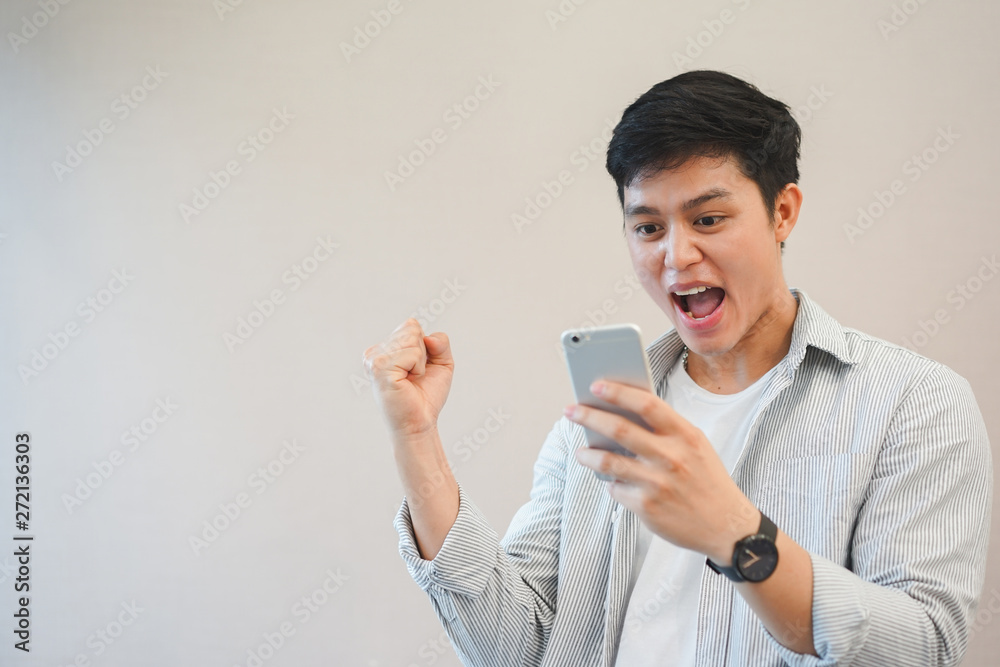 Close up young asian man raising hand with feeling success and happy after become winner in the online challenge competition , millennial and technology concept Close up young asian man raising hand with feeling success and happy after become winner in the online challenge competition , millennial and technology concept