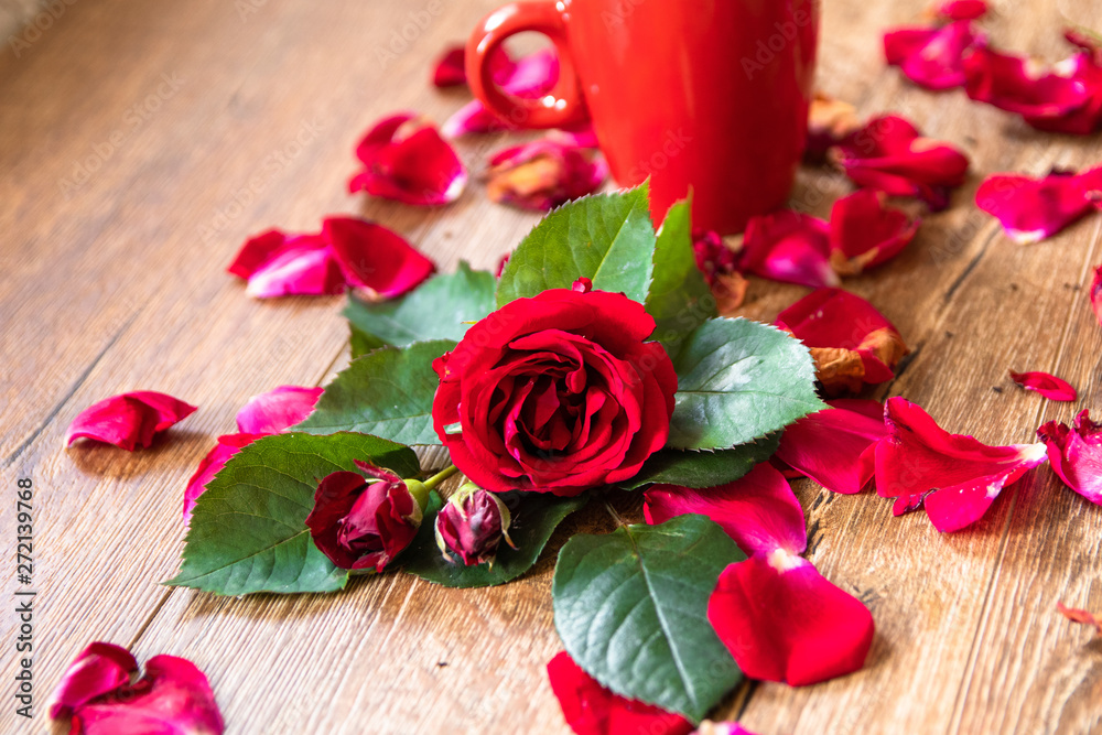 Red rose with leaves and red cup of coffee on wooden table Red rose with leaves and red cup of coffee on wooden table