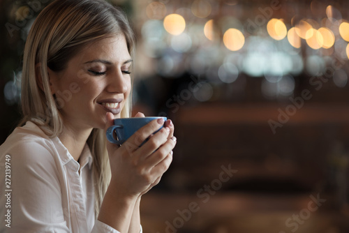 Close up of happy woman enjoying in the smell of fresh coffee in a cafe