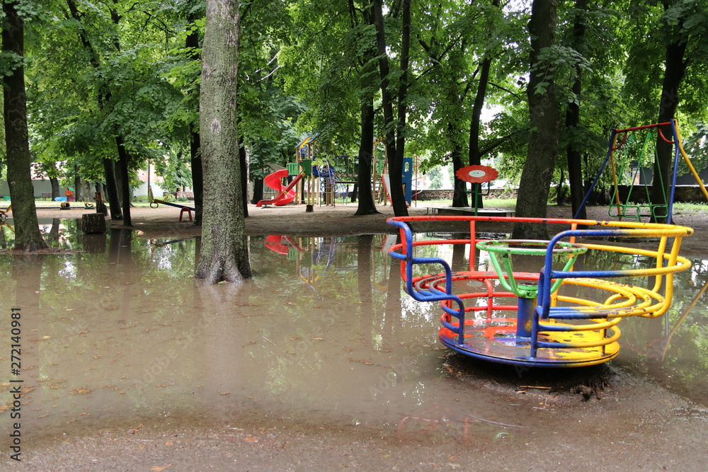 Colorful playground in the park after strong rain. Playground is flooded with water. Colorful playground in the park after strong rain. Playground is flooded with water.