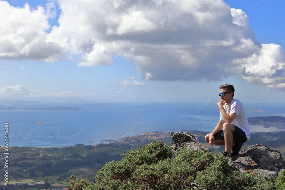 BOY MEDITATING ON THE HIGH OF A MOUNTAIN NEAR THE COAST ON SUMMER HOLIDAY