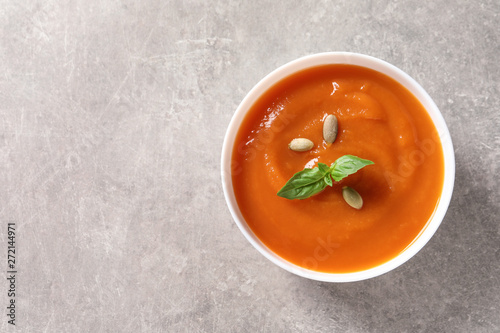 Bowl of tasty sweet potato soup on grey background, top view. Space for text