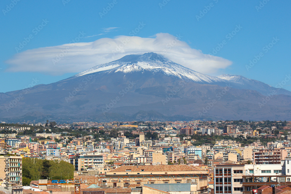 Majestic Mount Etna volcano with Italian city Catania at the foot of the mountain. Snow on the very top of the volcano. Etna is Sicilian major tourist attraction
