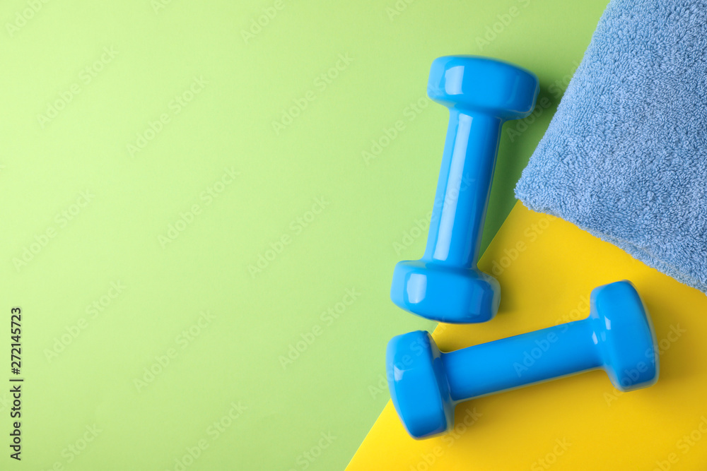 Vinyl dumbbells and towel on color background, flat lay. Space for text Vinyl dumbbells and towel on color background, flat lay. Space for text