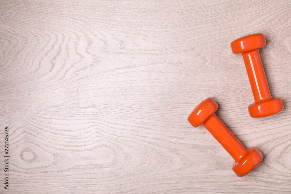 Vinyl dumbbells and space for text on wooden background, flat lay Vinyl dumbbells and space for text on wooden background, flat lay