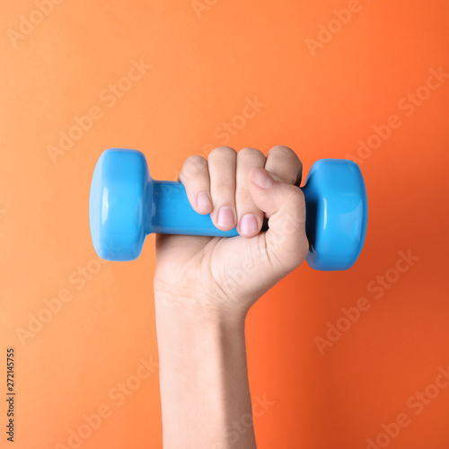 Woman holding vinyl dumbbell on color background, closeup