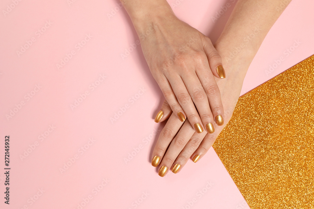 Fototapeta Woman showing manicured hands with golden nail polish on color background, top view. Space for text