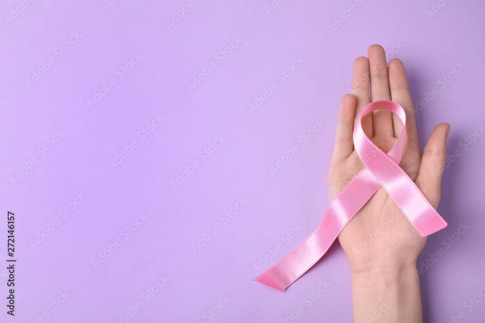 Woman with symbolic ribbon of breast cancer awareness and space for text on color background, top view. Gynecological care Woman with symbolic ribbon of breast cancer awareness and space for text on color background, top view. Gynecological care