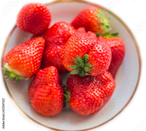 plate full of ripe strawberries on white background