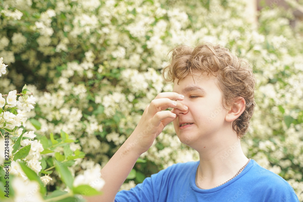 Teenager with allergies standing in a blue t-shirt among the Jasmine bushes and suffers from bad health Teenager with allergies standing in a blue t-shirt among the Jasmine bushes and suffers from bad health