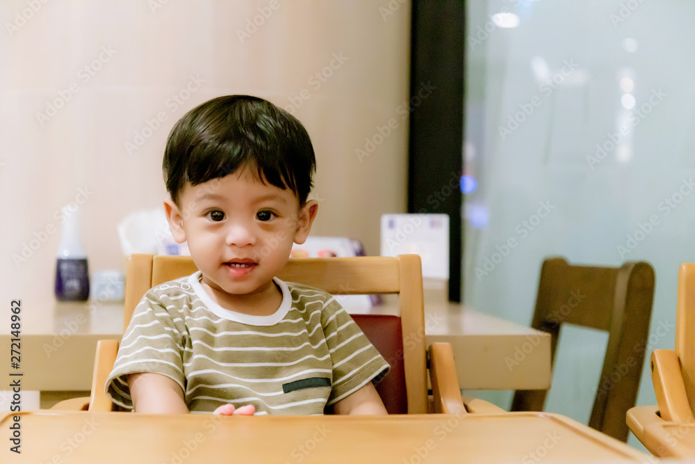 Portrait Of Happy Young Baby Boy In High Chair. Child sitting at empty table.Baby nutrition concept.Food advertisement design. smiling baby sitting on baby Chair. Portrait Of Happy Young Baby Boy In High Chair. Child sitting at empty table.Baby nutrition concept.Food advertisement design. smiling baby sitting on baby Chair.
