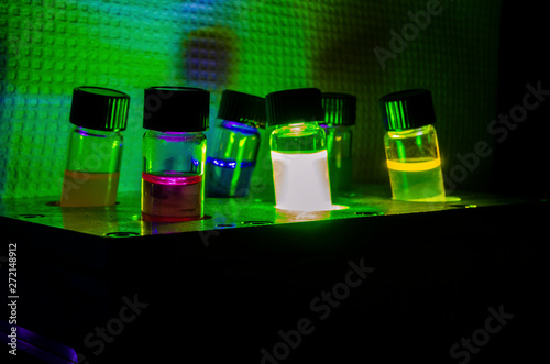 Multiple colourful light induced catalyst photochemical reaction side view in glass vial under green light in a dark chemistry laboratory