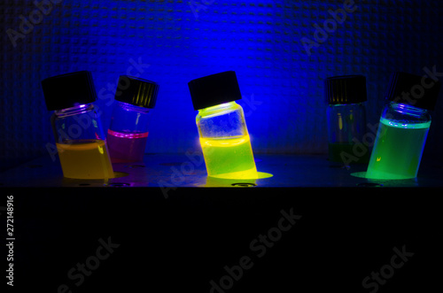 Multiple colourful light induced catalyst photochemical reaction side view in glass vial under UV light in a dark chemistry laboratory