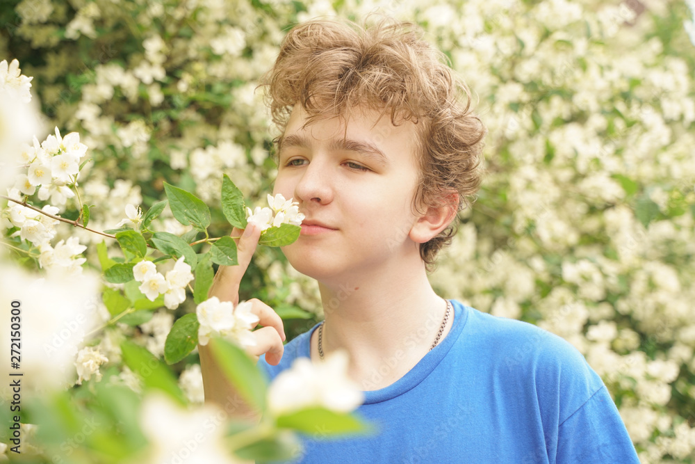 young man stands among the flowers and enjoys summer and flowering young man stands among the flowers and enjoys summer and flowering