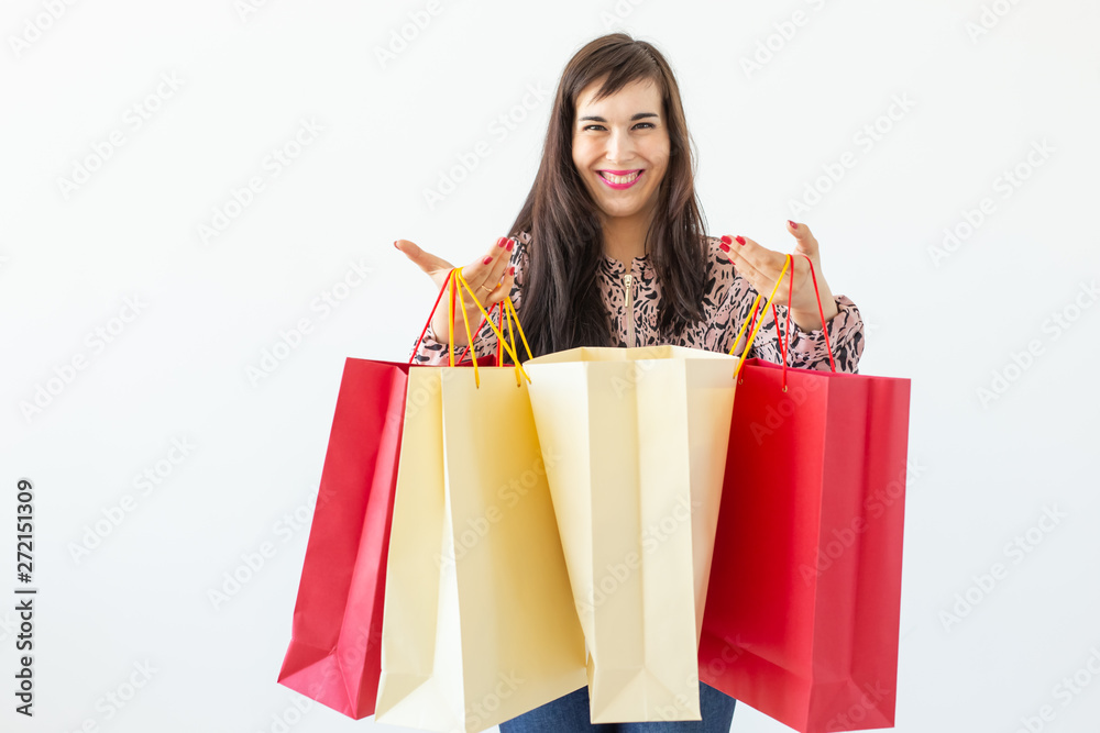 Joyful young brunette woman holding shopping bags posing on a white background. Concept of discounts and sales in the mall.