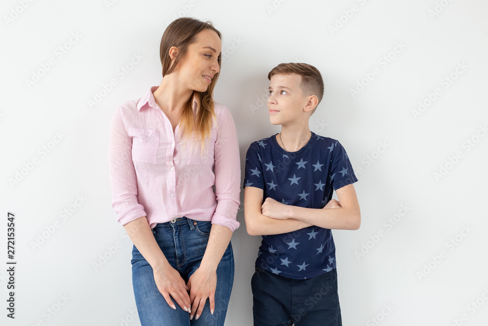 Charming young mother and a cute positive son are happy looking at each other while standing in the new living room after the move. The concept of good family relationships and relocation.