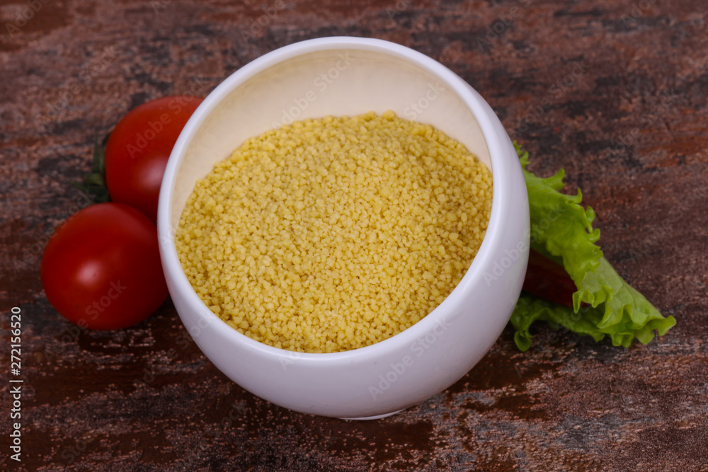 Raw couscous in the bowl served salad leaves, tomato and pepper Raw couscous in the bowl served salad leaves, tomato and pepper