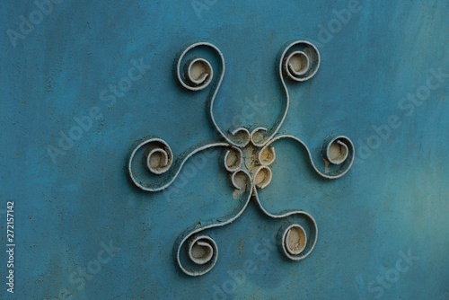 old forged pattern on the blue metal wall of the fence
