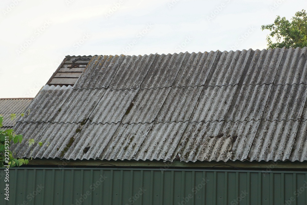 part of an old house with a roof under gray slate against the sky