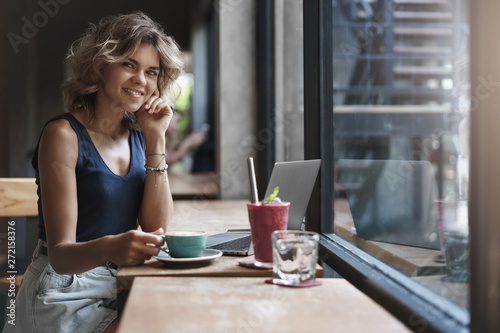 Charming successful young businesswoman working cafe restaurant sit near window enjoy tasty coffee smoothie use laptop prepare project, student studying before university exams