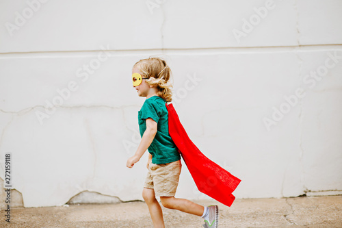 Little boy wearing cape dressed up like a superhero