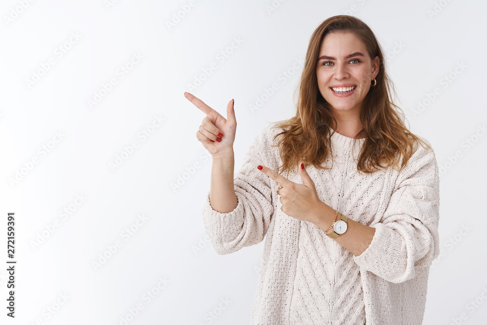 Girl inviting us come in drink coffee. Portrait friendly gorgeous charming woman wearing loose trendy sweater pointing left index fingers smiling broadly recommend product, adverisement Girl inviting us come in drink coffee. Portrait friendly gorgeous charming woman wearing loose trendy sweater pointing left index fingers smiling broadly recommend product, adverisement