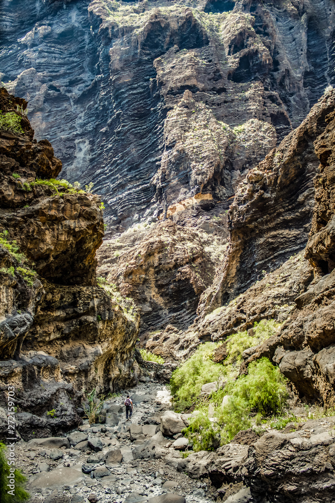 Obraz premium Rocks in the Masca gorge, Tenerife, showing solidified volcanic lava flow layers and arch formation. The ravine or barranco leads down to the ocean from a 900m altitude.