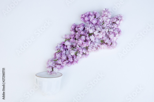 Romantic background with a cup of coffee  lilac flowers on a white table. Top view  place for text.