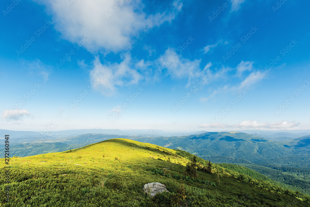 Fototapeta premium mountain landscape in dappled light. clouds on a blue sky above the green hill and distant ridges. fresh forenoon weather. vivid colors. summer travel and absolute freedom concept