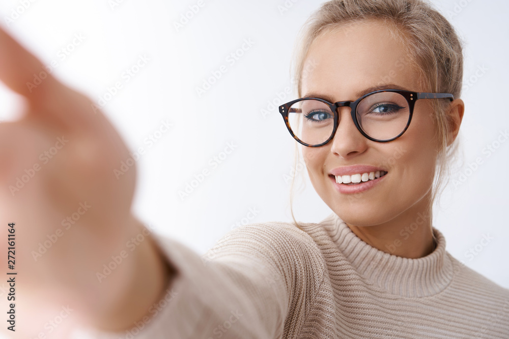 Close-up shot of attractive elegant businesswoman in glasses and blond combed hair extend hand holding camera taking selfie or recording video on smartphone smiling pleased and lovely over white wall Close-up shot of attractive elegant businesswoman in glasses and blond combed hair extend hand holding camera taking selfie or recording video on smartphone smiling pleased and lovely over white wall