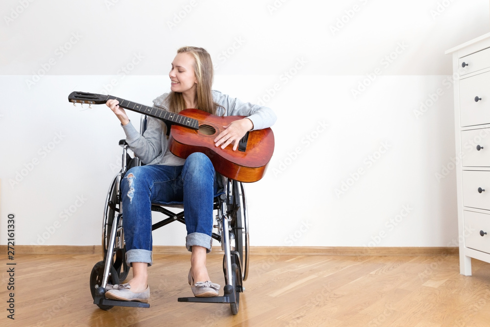 Invalid girl on wheelchair plays the guitar in day room.