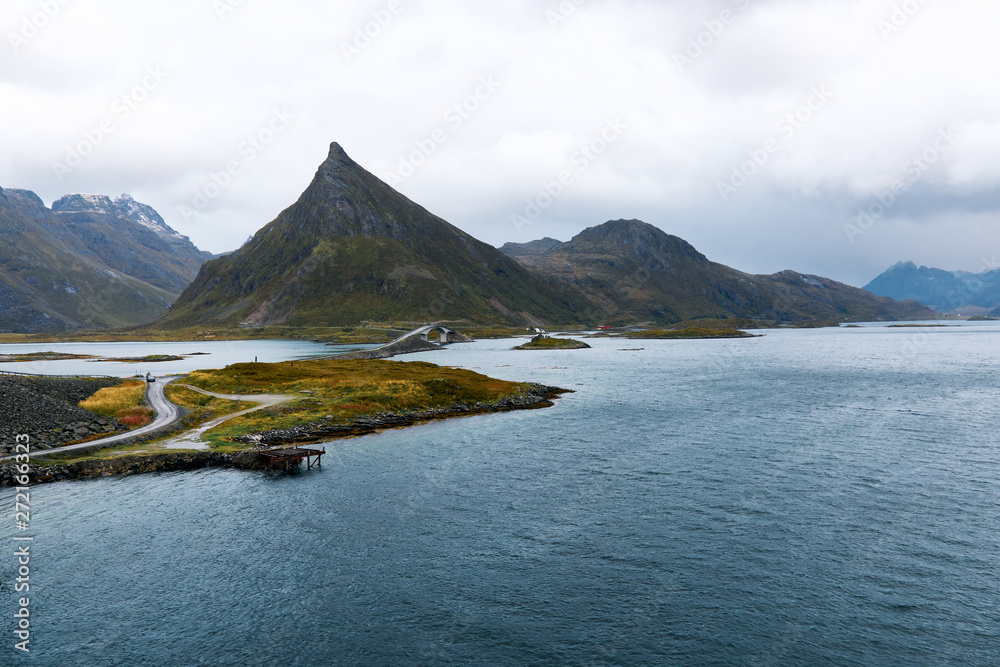 Empty road leading over the ocean on Lofoten Islands in Norway. The road is surrounded by mountains and water.