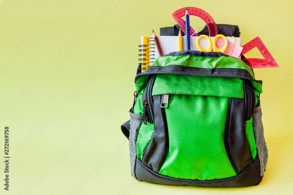 Composition with backpack and school stationery on yellow background Composition with backpack and school stationery on yellow background