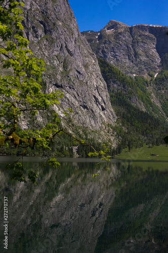 Alpine lake in the spring Alps. View of the shore from the hut of the alpine lake. Reflection of mountains in the crystal clear water of the lake.