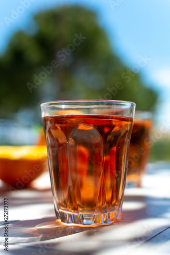 Young rose wine served outside in garden on white table with fresh orange in sun lights
