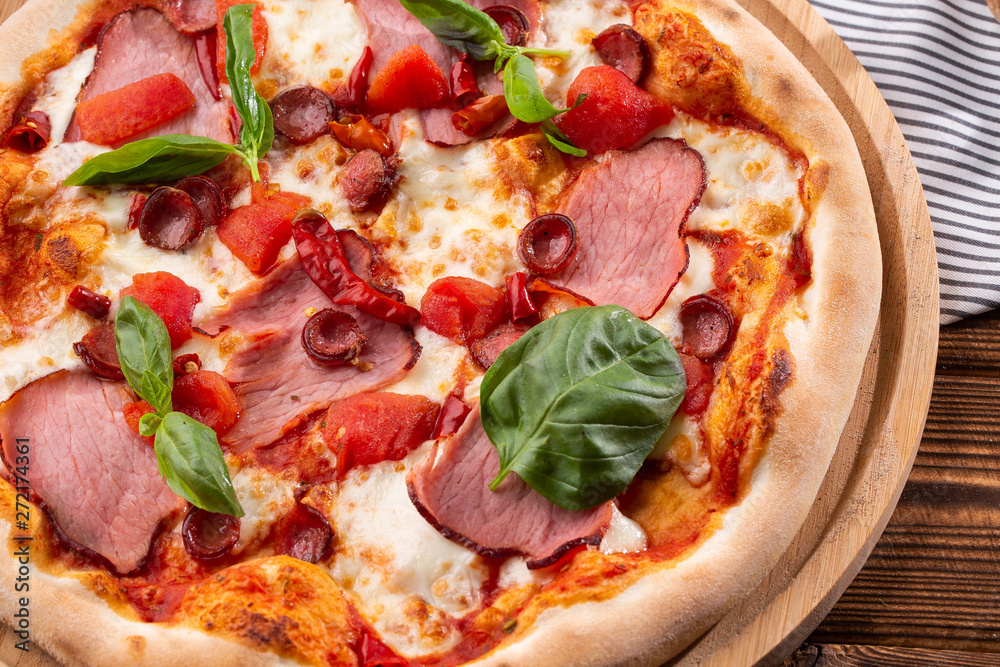 Pizza with ham , arugula (salad rocket), rucola and mozzarella on wooden background close up. Italian cuisine. Pizza with ham , arugula (salad rocket), rucola and mozzarella on wooden background close up. Italian cuisine.